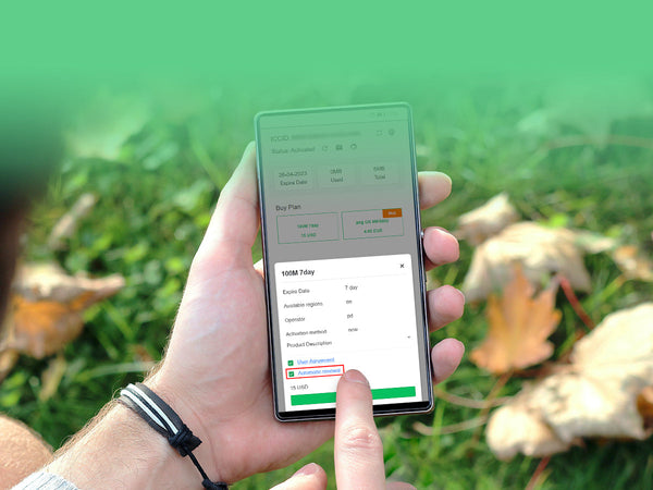 A person holding a smartphone outdoors, with their finger pointing at the screen to select an option from a pop-up menu within an app. The background shows green grass and autumn leaves.