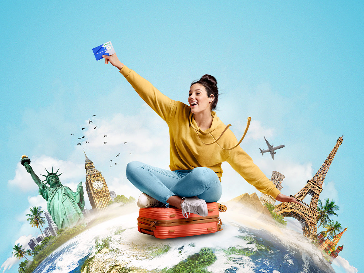A female traveler holding an international SIM card sits on a suitcase on top of the globe surrounded by world landmarks.