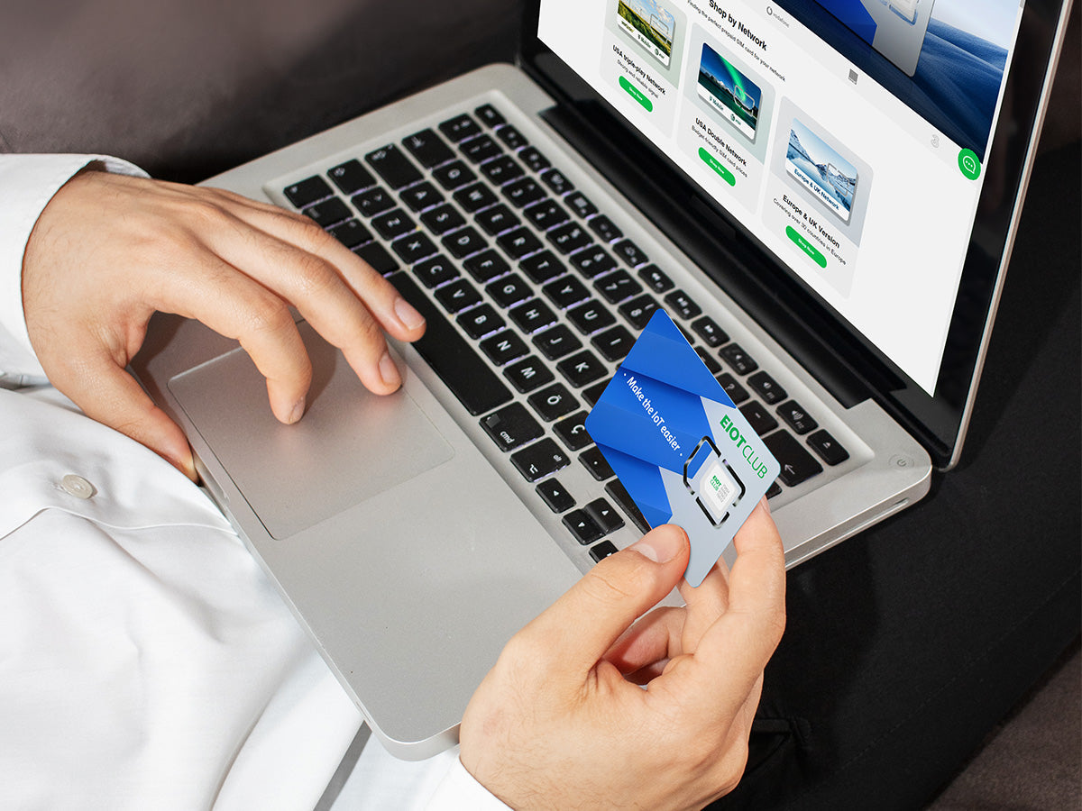 A person holding a SIM card while using a laptop.