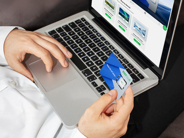 A person holding a SIM card while using a laptop.